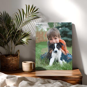 May include: A rectangular canvas print featuring a stylized illustration of a child with brown hair wearing an orange shirt, embracing a black and white puppy in a grassy outdoor setting with green foliage in the background.