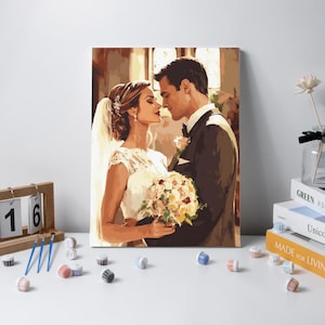 May include: A paint-by-numbers canvas featuring a wedding scene with a person in a white lace dress and veil holding a floral bouquet, standing next to a person in a dark suit. The artwork displays warm tones and soft lighting in a romantic setting.