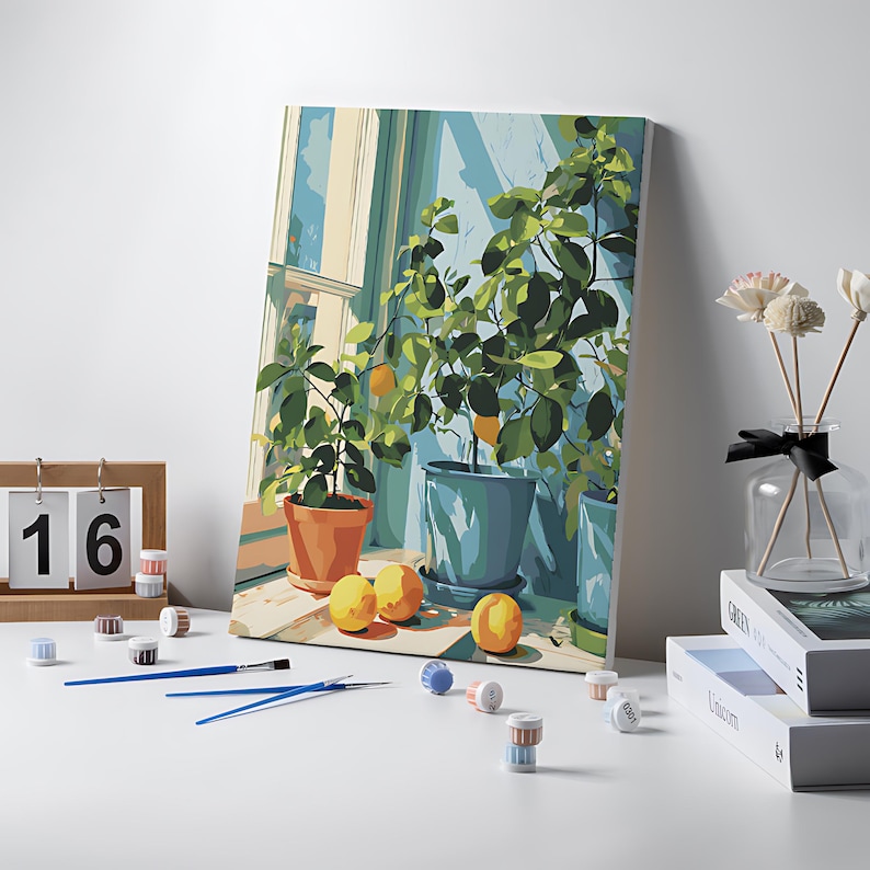 May include: A paint-by-numbers canvas featuring a vibrant lemon tree scene in a window. The artwork includes potted plants, lemons, and a window frame. Paint pots, brushes, and a wooden calendar with the number 16 are also visible.