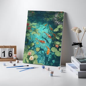 May include: A paint-by-numbers kit featuring a canvas with a koi pond scene. The artwork depicts orange and white koi fish swimming in a turquoise pond with lily pads and lotus flowers. Includes paint pots, brushes, and a wooden calendar showing the number 16.
