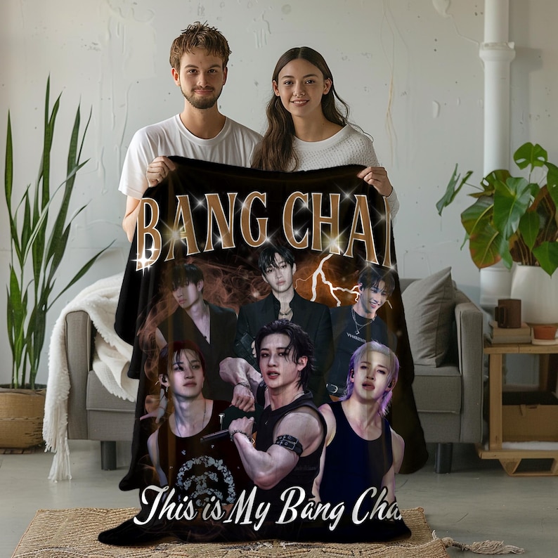 May include: Black blanket with the gold text "BANG CHAN" and images of a musical group. The blanket also has the text "This is My Bang Chan" in white. A man and a woman are holding the blanket. The blanket is a decorative item.