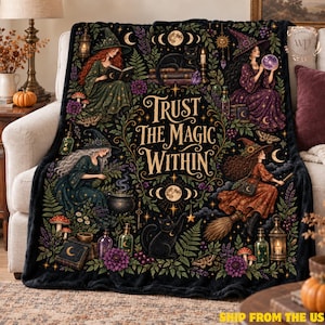 May include: A black fleece throw blanket featuring the text Trust The Magic Within in gold lettering. The design includes four witches, black cats, crystal balls, cauldrons, potion bottles, mushrooms, and botanical elements in vibrant colors.