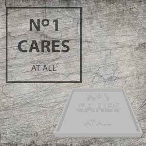Op de afbeelding: Een grijze, getextureerde achtergrond met de tekst "Nº1 CARES AT ALL" in een zwart vierkant. Daaronder een grijze, rechthoekige lade met dezelfde tekst in 3D-effect.