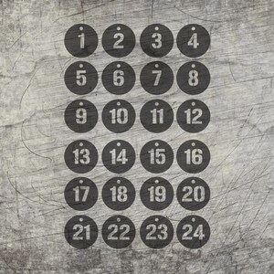 May include: Twenty-four black circular tags with white numbers 1 through 24 arranged in a grid pattern. Each tag has a small hole at the top. The background is a textured, gray surface.