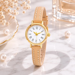 May include: A gold-toned wristwatch with a white face and Roman numeral hour markers. The watch has a light brown leather band and gold hands. The watch face is approximately 1 inch in diameter.
