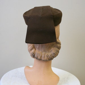 May include: A brown felt hat with a wide brim and a tall crown. The hat is sitting on a mannequin's head.