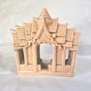 May include: A peach-colored ceramic pagoda with intricate architectural details. The structure features multiple tiers, arched openings, and a detailed roof design. The pagoda is a decorative item, likely for home decor.