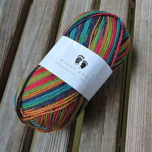 以下が含まれることがあります： HAPPY FEET 75% Superwash Wool | 25% Nylonと書いてあるラベルが付いたカラフルな糸の玉。