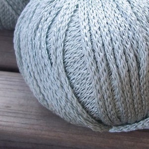 Könnte beinhalten: Eine Knäuel hellblaues Garn. Das Garn ist aus einem weichen, glatten Material und hat einen dezenten Glanz.