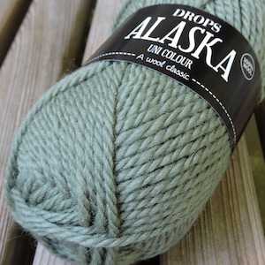 May include: A ball of Drops Alaska yarn in a green color. The label reads "Drops Alaska Uni Colour A wool classic 100% wool."