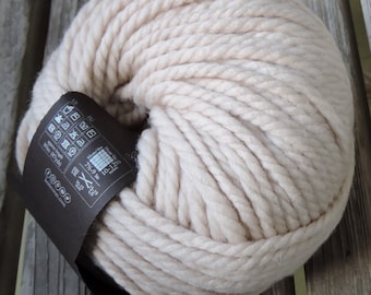 May include: A skein of beige yarn, with a brown label that includes care instructions and yarn weight information.