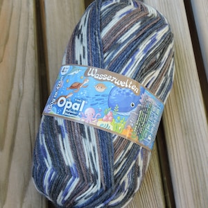 May include: A ball of blue, brown, and white yarn with a label that reads "Opal Wasserwelten 100g ca. 425m 4-fach Pullover & Sockenwolle".