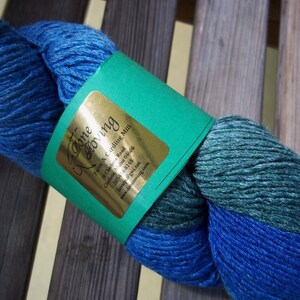 K&ouml;nnte beinhalten: Blau-gr&uuml;nes Garnkn&auml;uel mit einem Etikett mit der Aufschrift "Done Moving Farm & Carding Mill 20 Charlotte Road Charlotte, Maine 04666 207-454-8148 Farrarps@gwi.net www.deneroving.com"