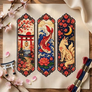 Peut inclure: Trois motifs de point de croix verticaux sur tissu beige. Le gauche montre un torii rouge et une montagne. Le centre présente un poisson koi rouge nageant dans l'eau bleue avec un lotus. Le droit dépeint un renard à plusieurs queues sous un croissant de lune jaune.