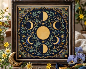 May include: A framed cross-stitch embroidery featuring a central full moon surrounded by various lunar phases in yellow and blue on a dark navy background, accented with green foliage and small stars, all enclosed in a dark brown wooden frame.