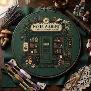 May include: A circular embroidery hoop containing a cross-stitch design of a shop storefront labelled Mystic Alchemy Elemental Elixirs & Herbs. The dark green fabric features shelves with bottles, books, a black cat, mushrooms, and a sign that says Open.