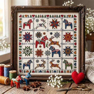 Peut inclure: Un échantillon de point de croix encadré sur tissu crème présentant un motif en grille avec des chevaux de Dala rouges, bleus et verts, des rennes et des étoiles géométriques multicolores. La bordure est ornée de cœurs, d'arbres et de losanges.