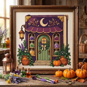 May include: A cross-stitch embroidery in a dark wood frame depicting a purple book-shaped shop with a green door, a crescent moon, a lantern, and shelves of colourful potion bottles, flanked by potted plants and orange pumpkins.