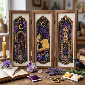 Könnte beinhalten: Ein Triptychon aus drei gerahmten Kreuzstichbildern in Holzrahmen. Die Bilder zeigen dunkelviolette und goldene Motive, darunter ein Bibliotheksbogen, ein Rabe mit einem offenen Buch und ein hoher Turm auf cremefarbenem Stoffhintergrund.