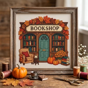 Könnte beinhalten: Ein gerahmtes Kreuzstichbild, das die Fassade eines Buchladens mit einer türkisfarbenen Tür, Bücherregalen, einem gemütlichen Sessel und Herbstblättern zeigt. Das Wort BOOKSHOP ist in schwarzen Buchstaben über der Tür gestickt.