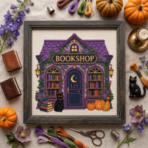 Peut inclure: Une broderie au point de croix encadrée représentant une librairie violette avec un croissant de lune jaune sur la porte, un chat noir, des piles de livres et des citrouilles. Le bâtiment porte l'inscription BOOKSHOP, entouré de vignes et lanternes.