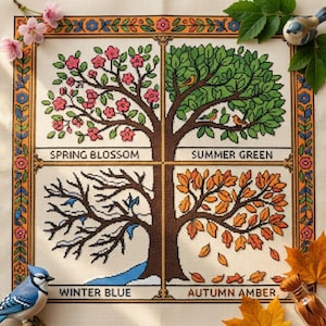 Könnte beinhalten: Eine Kreuzstichstickerei auf Stoff, die vier Jahreszeiten in einem Raster darstellt. Oben links sind rosa Blüten mit der Aufschrift SPRING BLOSSOM, oben rechts grüne Blätter mit SUMMER GREEN, unten links kahle Äste mit WINTER BLUE und unten rechts orangefarbene Blätter mit AUTUMN AMBER zu sehen.