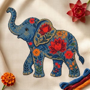 May include: A cross-stitch embroidery pattern on cream fabric featuring a blue elephant decorated with vibrant red, orange, and green floral motifs. The design includes large lotus-like flowers and smaller blossoms, accompanied by loose embroidery thread.