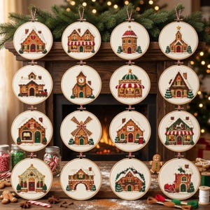May include: Sixteen circular embroidery hoops featuring detailed gingerbread house designs with snow-covered roofs, festive decorations, and architectural elements like clocks, windmills, and shops, all displayed in a grid arrangement.