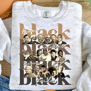 May include: Pale grey sweatshirt with a graphic design. The design features the word "Black" in shades of brown, alongside the words "love", "excellence", "history", "joy", and "pride". Portraits of notable figures are included.