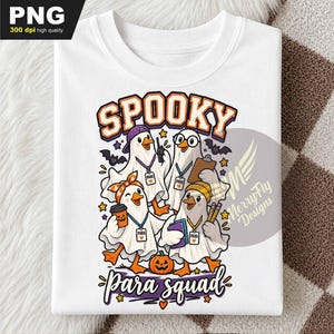 May include: A white t-shirt featuring a graphic of four ducks dressed as ghosts for Halloween. The text reads SPOOKY at the top and Para squad at the bottom. The ducks wear accessories including a purple cap, glasses, a headband, and a beanie.