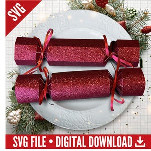 Puede incluir: Dos petardos navideños rojos brillantes con cintas rosas, presentados en un plato blanco con adornos festivos. La imagen incluye el texto "SVG FILE • DIGITAL DOWNLOAD".