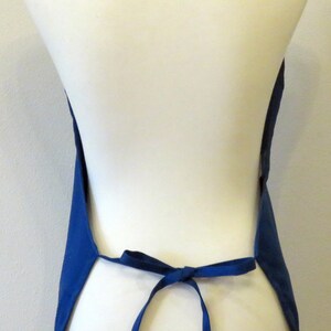 May include: A blue apron with adjustable straps. The apron is tied at the waist and has a simple design.