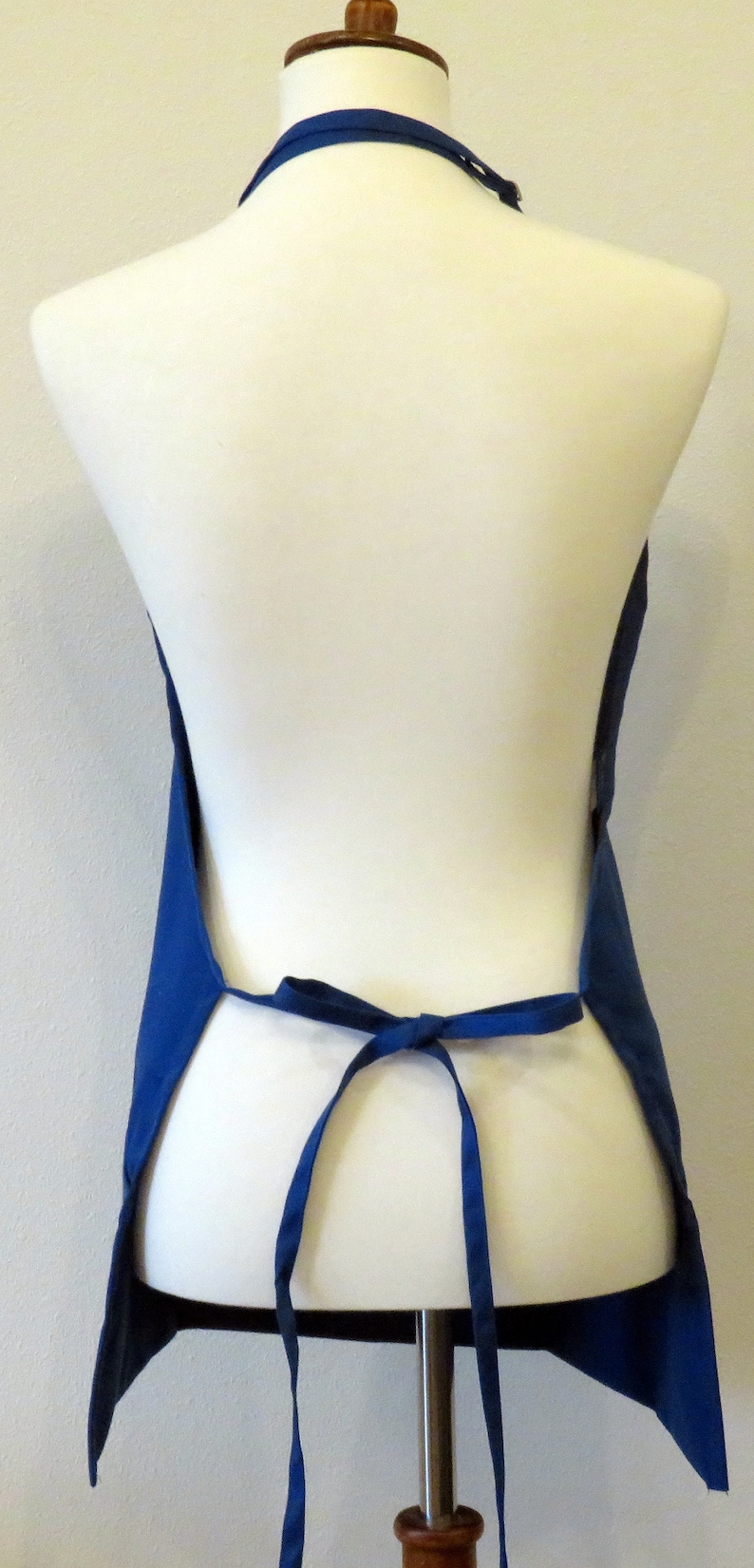 May include: A blue apron with adjustable straps. The apron is tied at the waist and has a simple design.