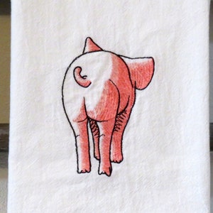 May include: Embroidered kitchen towel featuring a pink pig with its back turned to the viewer. The pig is outlined in black thread and has a pink tail.