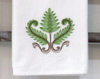 May include: White kitchen towel with an embroidered green fern design.