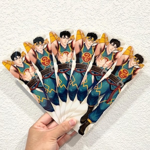 May include: A hand fan featuring a repeating illustration of a character in a teal and gold outfit with a mask. The character has black hair and is posed with their arms behind their head. The fan is held in a hand against a white background.