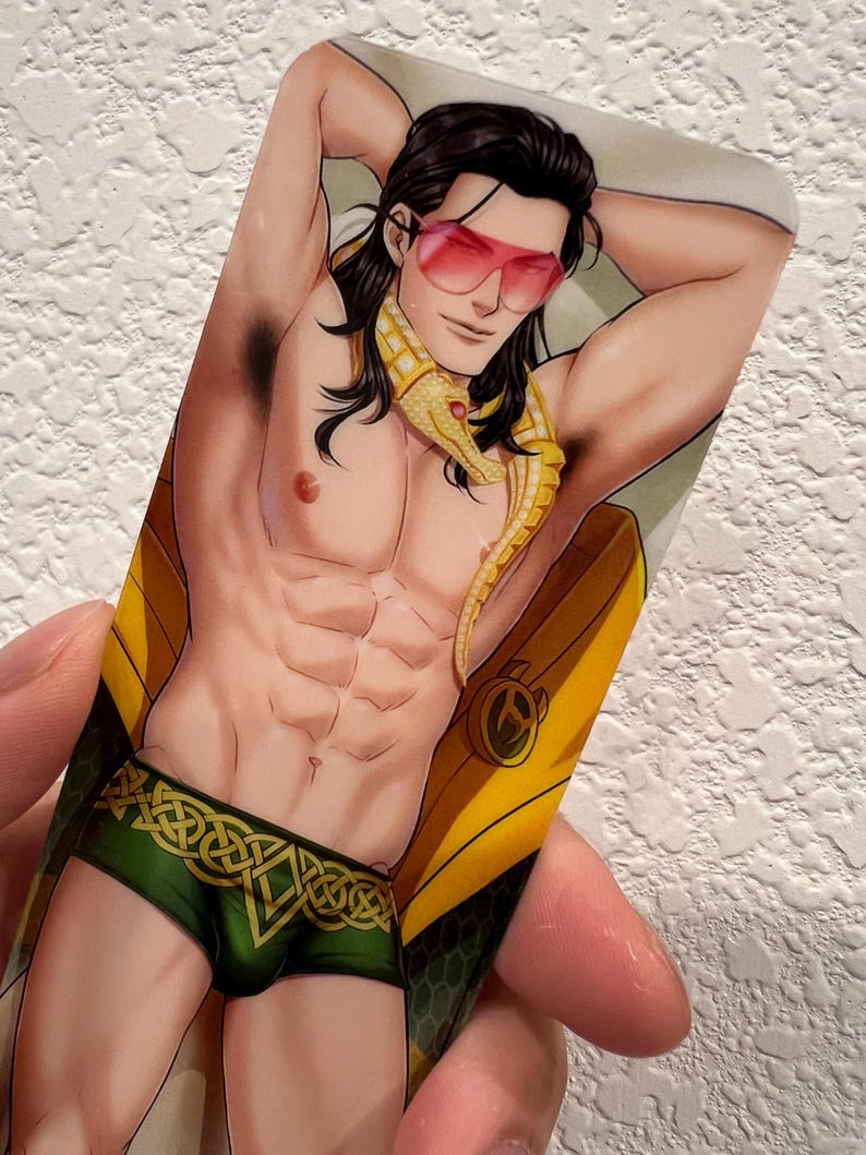 May include: An illustrated card featuring a muscular figure with long black hair, wearing pink sunglasses and green and gold briefs. A yellow and gold snake-like accessory is draped around the neck. The card has a glossy finish.