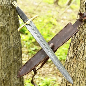 May include: A detailed image of a sword with a patterned blade and a gold-colored crossguard. The handle is wrapped in a dark material. The sword is sheathed in a brown leather scabbard. The image is set against a natural background.