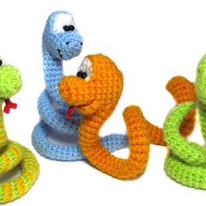 May include: Three crocheted snake toys in different colors: green, blue, and orange. Each snake has a red tongue and black eyes.