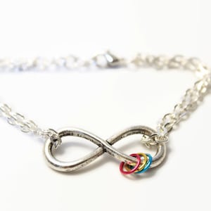 May include: A silver infinity symbol charm bracelet with a chain and colourful rings attached to the symbol.