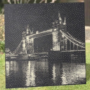 May include: A square black canvas featuring a pointillist illustration of Tower Bridge in London. The image is composed entirely of small, light-colored dots against the dark background, depicting the bridge structure and its reflection in water.
