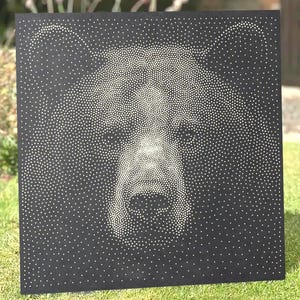 Könnte beinhalten: Eine quadratische schwarze Platte mit einem punktierten Design eines Bärengesichts, das aus zahlreichen kleinen weißen Punkten besteht. Die Dichte der Punkte variiert, um die Gesichtszüge des Bären, einschließlich Augen, Schnauze und Ohren, zu bilden.