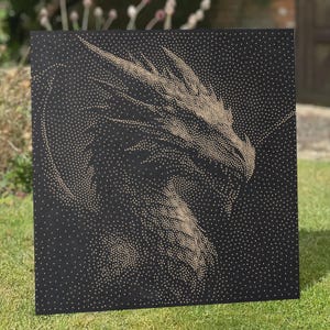 Puede incluir: Un lienzo cuadrado negro que presenta una ilustración de una cabeza de dragón al estilo puntillista, creada con numerosos puntos pequeños de color claro. El dragón está representado de perfil, mirando a la derecha, con sus escamas y rasgos definidos.