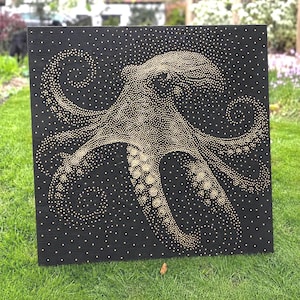 May include: A square black wooden panel featuring a pointillist octopus design created with numerous small gold-coloured dots. The octopus is centred on the panel, with its tentacles extending outwards in a spiral pattern across the dark surface.