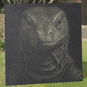 Pode incluir: Um painel quadrado preto apresentando um retrato pontilhado de um lagarto criado com numerosos pequenos pontos brancos. Os pontos variam em densidade para formar os traços faciais detalhados, olhos e escamas do réptil contra o fundo escuro.