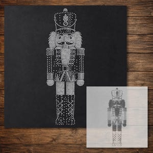 May include: A nutcracker design composed of white dots on a black background, featuring a tall hat, a uniform with epaulets, and tall boots. A smaller, semi-transparent version of the same nutcracker design is positioned in the bottom right corner.