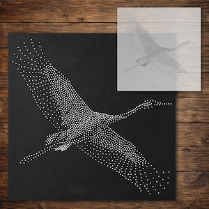 Könnte beinhalten: Eine quadratische Schablone mit einem pointillistischen Design eines fliegenden Kranichs. Der Vogel besteht aus zahlreichen kleinen weißen Punkten auf einem einfarbigen schwarzen Hintergrund und bildet eine detaillierte Silhouette.