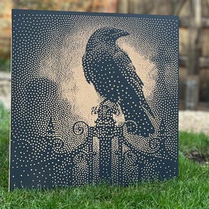 May include: Square artwork featuring a black raven perched on a decorative element, set against a beige background. The raven and background are created using a dot pattern on a dark blue surface. The artwork is displayed on green grass.