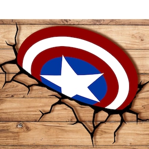 Pode incluir: Um design de escudo do Capitão América, com um anel externo listrado em vermelho e branco, um círculo interno azul com uma estrela branca e uma borda preta rachada, em um fundo de madeira.