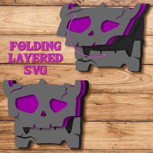 May include: A digital graphic design file featuring a folding layered SVG of a grey, cracked skull-like creature with vibrant purple accents. The text FOLDING LAYERED SVG is displayed in purple on the left side of the image.